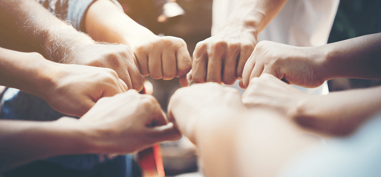 Community Group of diverse people joining fists in a symbol of teamwork and collaboration, representing versatility and collective effort.